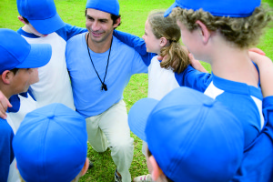 Little league baseball team in huddle with their coach